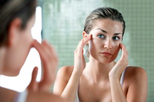 Mujer aplicándose crema delante del espejo